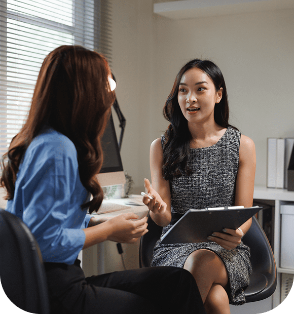 Two women engaged in a professional conversation in an office setting.